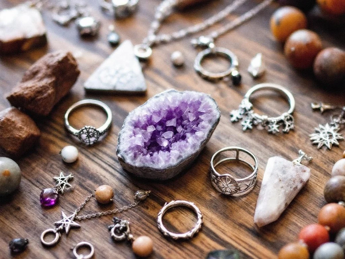 Natural stone beads, rings and jewellery on a wooden surface